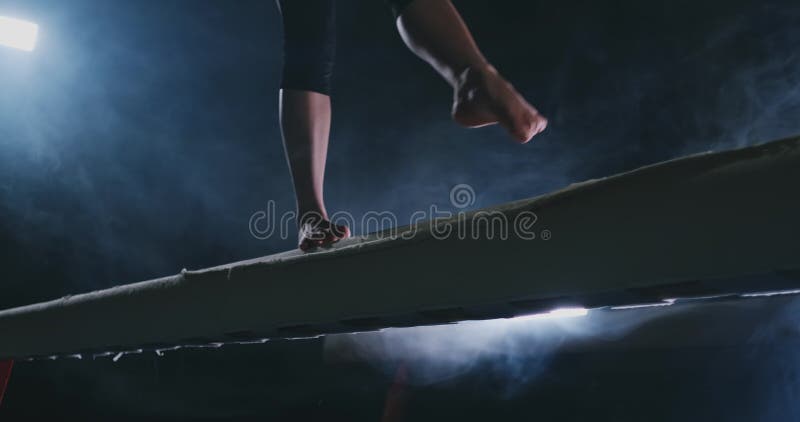 Lägger benen på ryggen den yrkesmässiga flickan som gymnaster hoppar i ultrarapid i röken på balansbommen Kvinnors konstnärliga g stock video