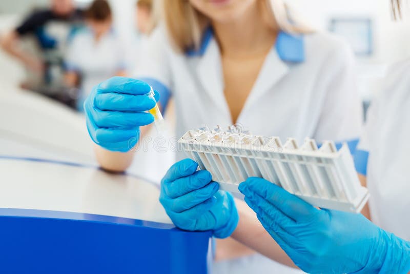 Medical and science background. Hands of laboratory assistants holding rack of sample tubes for blood test analysis. Medical and science background. Hands of laboratory assistants holding rack of sample tubes for blood test analysis.