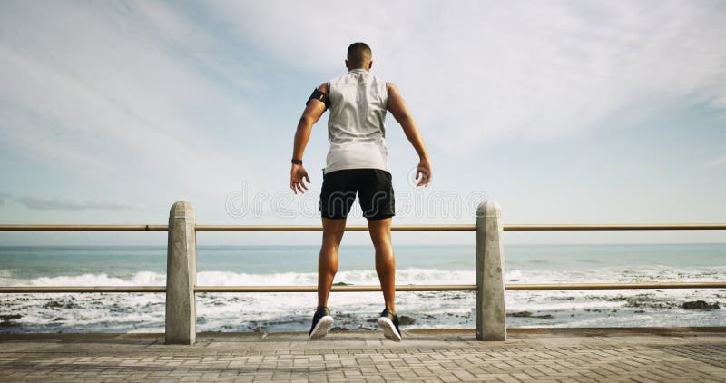Lämplighetsstrand och baksida av människan med träning eller maratonutbildning utomhus för hastigheter. hoppa varmt upp och man arkivfoto