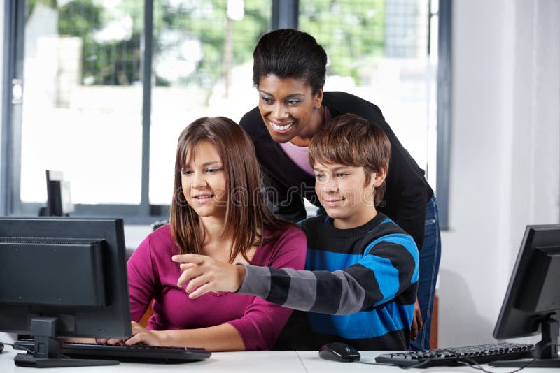 Lärare Assisting Teenage Students i datorlabb royaltyfri foto Lärare Assisting Teenage Students i datorlabb royaltyfri foto