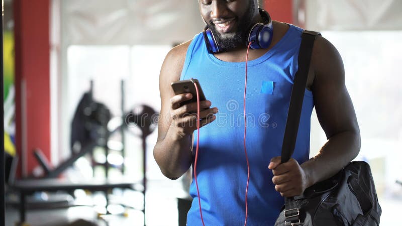 Läs- meddelande för stilig idrotts- man på mobiltelefonen med lyckligt leende på framsida