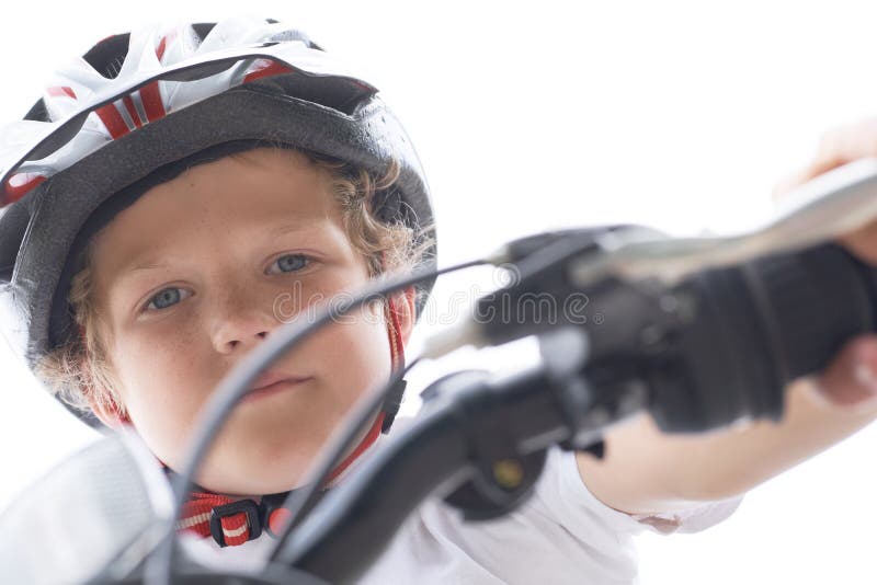 Lågvinkelsikt för en leende ung pojke i en hjälm som cyklar på sommarparken arkivbilder