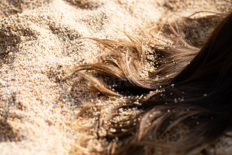 Långt brunt hår på sand arkivbild Långt brunt hår på sand arkivbild