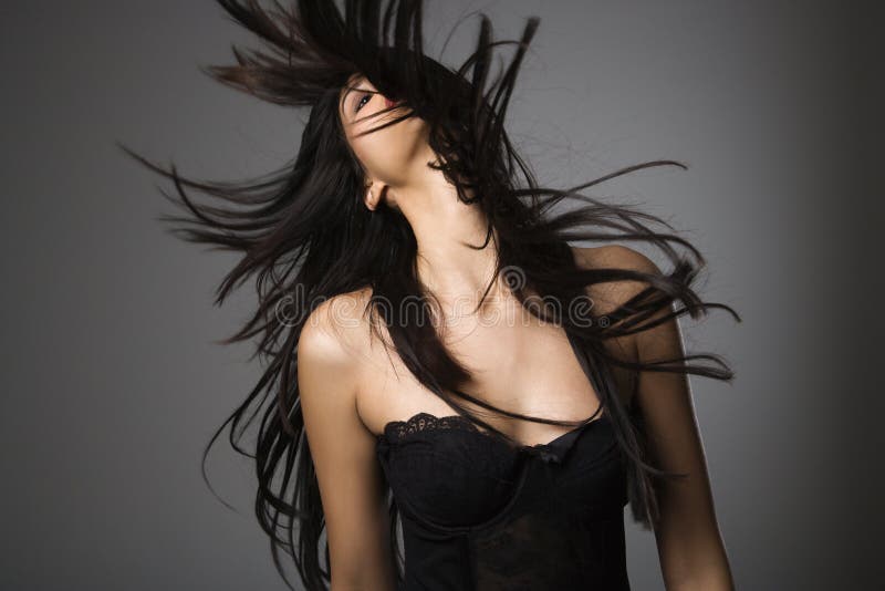 Portrait of pretty young woman flinging long black hair into air. Portrait of pretty young woman flinging long black hair into air.