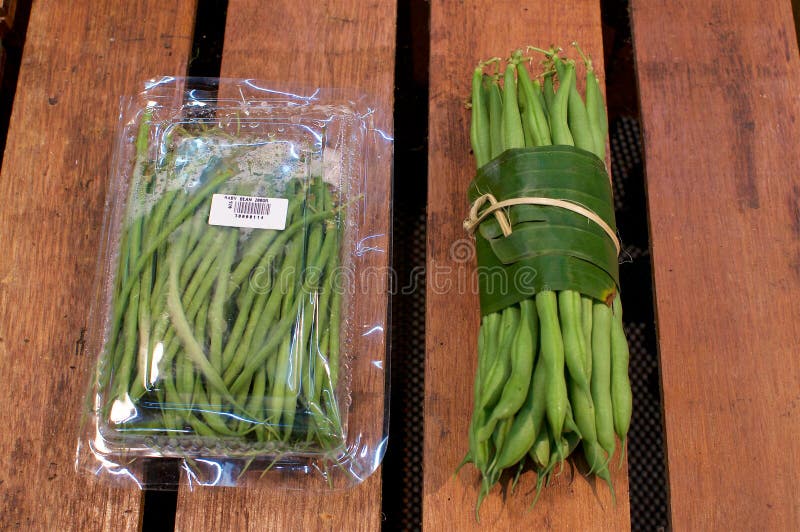 Légume enveloppé dans des feuilles de banane contre Conditionnement en plastique photos stock Légume enveloppé dans des feuilles de banane contre Conditionnement en plastique photos stock