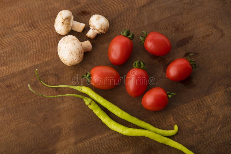 Légume : Vue supérieure des tomates rouges fraîches de bébé, des champignons et des piments verts sur le fond en bois de Brown photo stock Légume : Vue supérieure des tomates rouges fraîches de bébé, des champignons et des piments verts sur le fond en bois de Brown photo stock