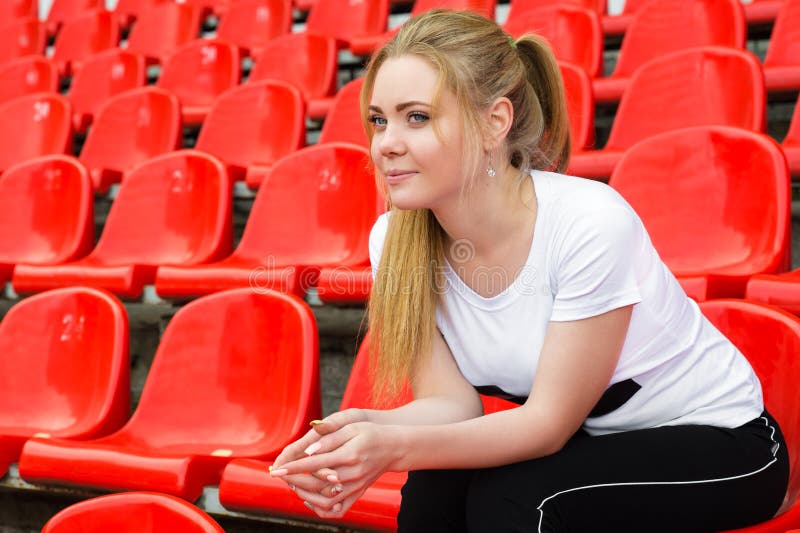 Líder da claque bonito da mulher que senta-se no pódio do estádio foto de stock Líder da claque bonito da mulher que senta-se no pódio do estádio foto de stock