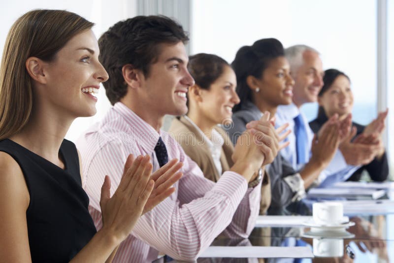 Línea de hombres de negocios que escuchan la presentación asentada en Glas foto de archivo Línea de hombres de negocios que escuchan la presentación asentada en Glas foto de archivo