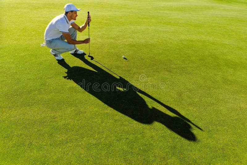 Línea masculina del control del golfista para poner la pelota de golf fotografía de archivo Línea masculina del control del golfista para poner la pelota de golf fotografía de archivo