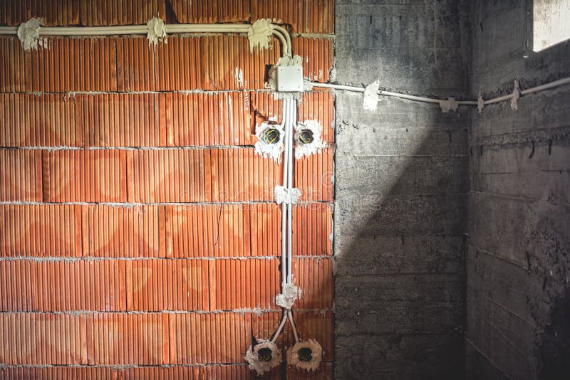 Líneas eléctricas construcción en el estado, los tubos de la electricidad y las paredes de ladrillo bajo construcción imágenes de archivo libres de regalías