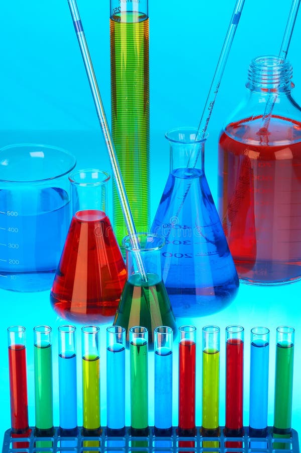 Many different coloured chemical solutions in laboratory glasses with pipettes on blue background. Many different coloured chemical solutions in laboratory glasses with pipettes on blue background