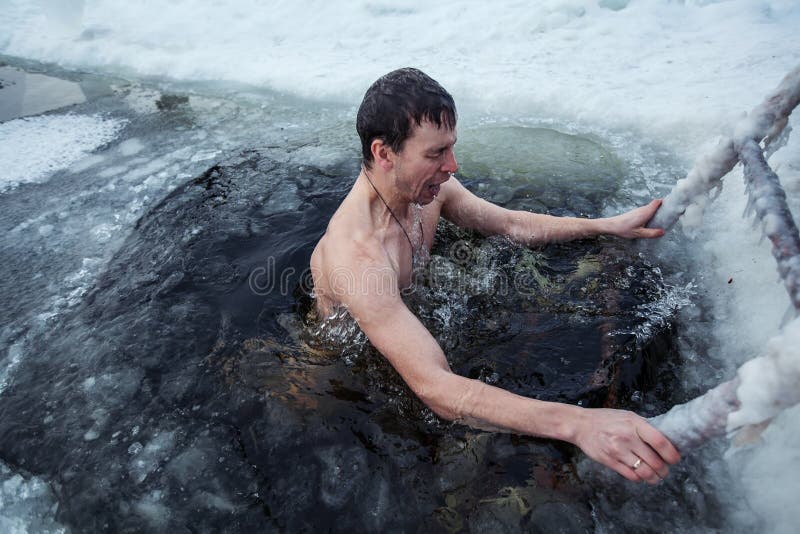 Young man swimming in an ice hole in a winter day. Young man swimming in an ice hole in a winter day