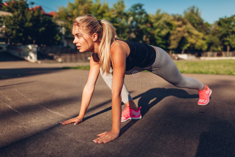Löpare för ung kvinna som får av till en tidig start på sportsground i sommar Sund livsstil royaltyfri foto Löpare för ung kvinna som får av till en tidig start på sportsground i sommar Sund livsstil royaltyfri foto