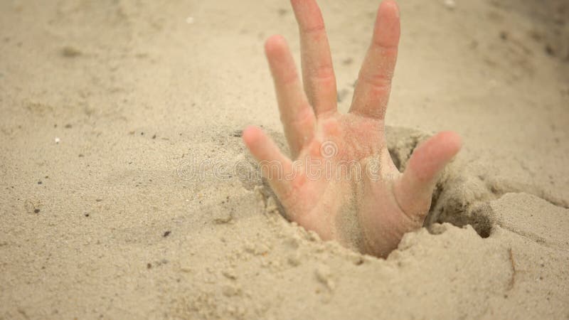 Mão afundando na areia movediça tentando tirar dicas para sobreviver no  deserto enterrado