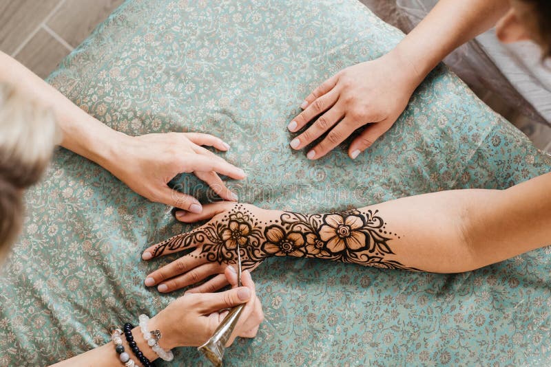 Artista aplicando tatuagem de henna mehndi na mão feminina