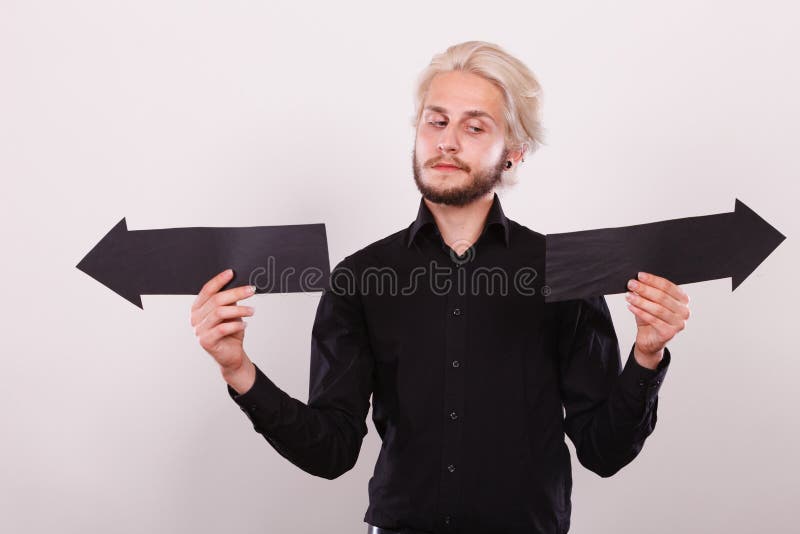 M??czyzna trzyma czarne strza?a wskazuje lewica i prawica obrazy stock M??czyzna trzyma czarne strza?a wskazuje lewica i prawica obrazy stock