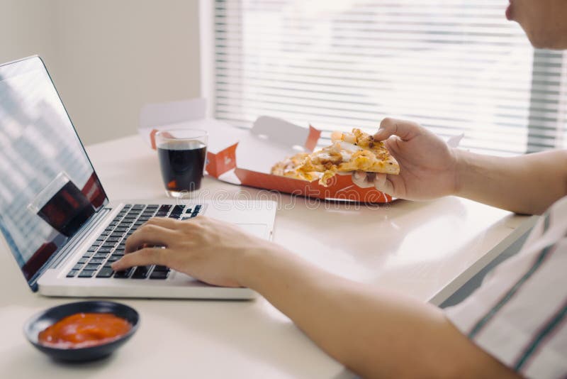 M?nnlicher Freiberufler, der Pizza beim B?ro zu Hause bearbeiten isst lizenzfreies stockbild M?nnlicher Freiberufler, der Pizza beim B?ro zu Hause bearbeiten isst lizenzfreies stockbild