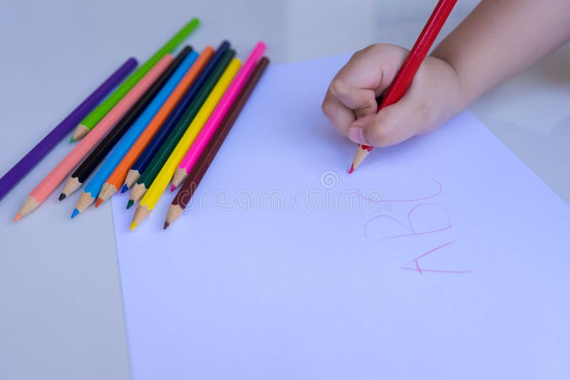A m?o da crian?a que prepara-se para escrever em uma folha de papel branca com l?pis coloridos Educa??o e conceito das atividades fotos de stock A m?o da crian?a que prepara-se para escrever em uma folha de papel branca com l?pis coloridos Educa??o e conceito das atividades fotos de stock