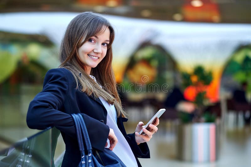 M?oda biznesowa kobieta u?ywa jej m?drze ono u?miecha si? i telefon zdjęcie royalty free M?oda biznesowa kobieta u?ywa jej m?drze ono u?miecha si? i telefon zdjęcie royalty free
