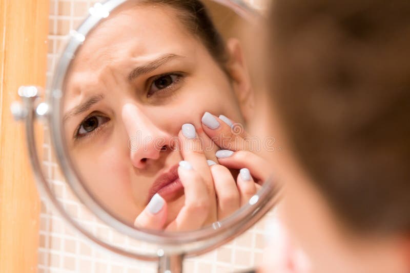 M?oda dziewczyna gniesie krost? na fer twarzy przed ?azienki lustrem Pi?kna skincare i wellness ranku poj?cie obraz royalty free M?oda dziewczyna gniesie krost? na fer twarzy przed ?azienki lustrem Pi?kna skincare i wellness ranku poj?cie obraz royalty free