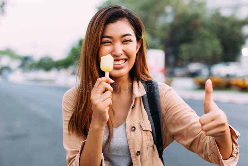 M?oda kobieta pokazuje aprobaty z popsicle lody w plenerowej scenie zdjęcie stock M?oda kobieta pokazuje aprobaty z popsicle lody w plenerowej scenie zdjęcie stock