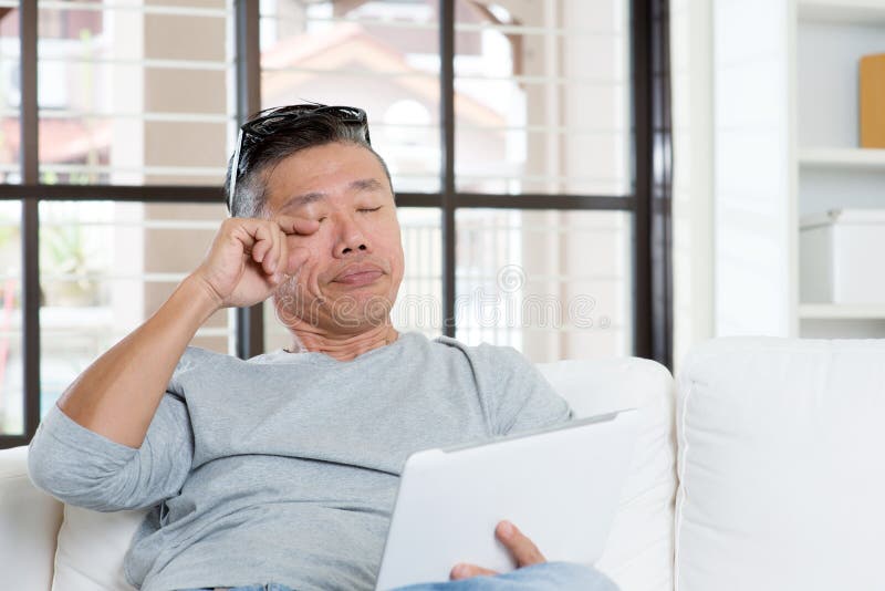Mûrissez la douleur de yeux asiatique d'homme tout en à l'aide de la tablette images stock Mûrissez la douleur de yeux asiatique d'homme tout en à l'aide de la tablette images stock