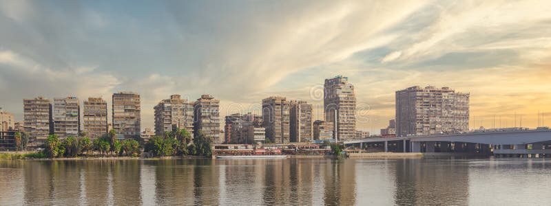 Maadi skyline è illuminata dai raggi solari dorati in Nilo riflettendo le città silhouette con il ponte montib cairo egypt fotografia stock libera da diritti