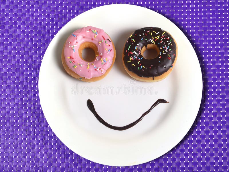Maakte het Smiley gelukkige gezicht op schotel met donutsogen en chocoladestroop als glimlach in suiker en zoete verslavingsvoedi stock afbeelding Maakte het Smiley gelukkige gezicht op schotel met donutsogen en chocoladestroop als glimlach in suiker en zoete verslavingsvoedi stock afbeelding