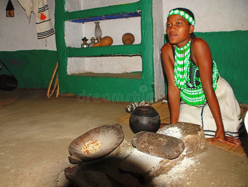 Maaltijd van de Zoeloes vrouwen de kokende maïs bij stammenhuis, Lesedi-Dorp stock fotografie Maaltijd van de Zoeloes vrouwen de kokende maïs bij stammenhuis, Lesedi-Dorp stock fotografie