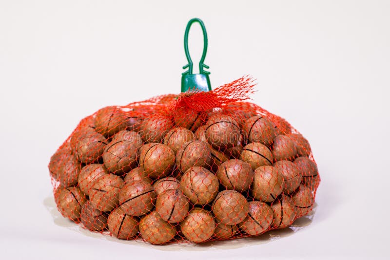 Macadamia Nuts in a Red Mesh Bag on a White Background Stock Photo