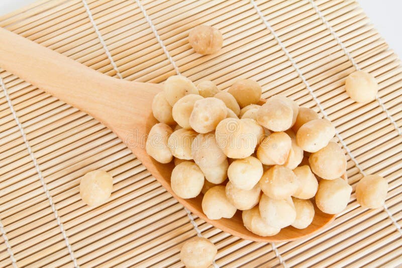 Macadamia nuts on wooden scoop isolated on white background