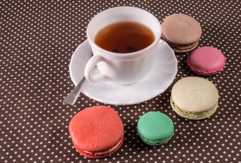 Macarons coloridos franceses dos bolos e um copo do chá foto de stock royalty free Macarons coloridos franceses dos bolos e um copo do chá foto de stock royalty free