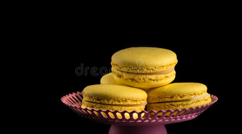 Macarons jaunes sur un fond noir. Pâtes françaises. Pile de macaron jaune avec isolée sur le fond noir foncé. Macarons.