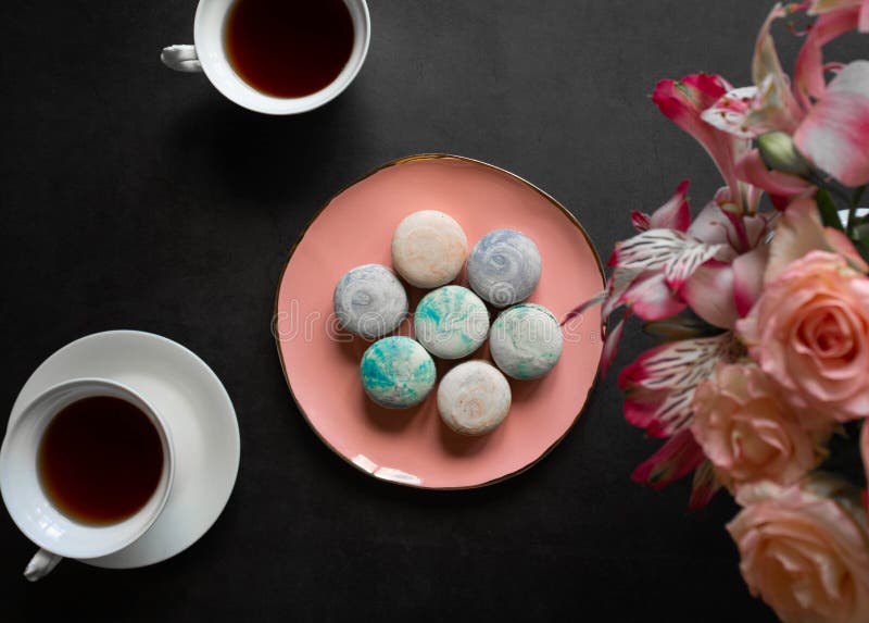 Macarons multicolores en la placa rosada en una tabla oscura taza blanca de té o de café desayuno con el postre Ramo de flores imagen de archivo libre de regalías Macarons multicolores en la placa rosada en una tabla oscura taza blanca de té o de café desayuno con el postre Ramo de flores imagen de archivo libre de regalías