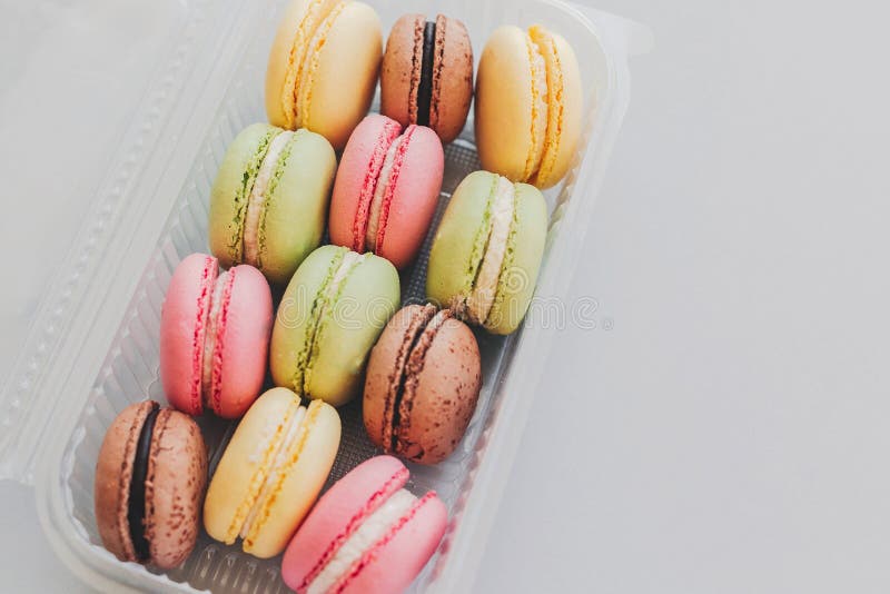 Macarrones coloridos deliciosos en caja plástica en gra en colores pastel de moda foto de archivo libre de regalías Macarrones coloridos deliciosos en caja plástica en gra en colores pastel de moda foto de archivo libre de regalías