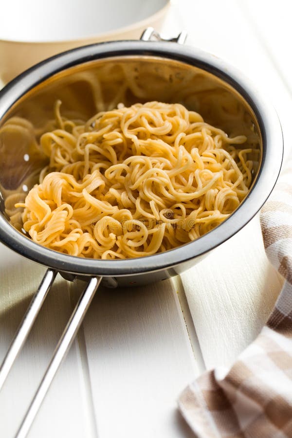 Boiled chinese noodles in colander on white wooden table. Boiled chinese noodles in colander on white wooden table