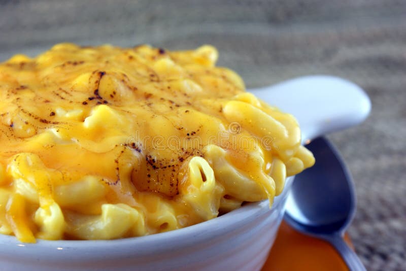 Homemade Mac-N-Cheese with golden top presented in white bowl with blurred background. Homemade Mac-N-Cheese with golden top presented in white bowl with blurred background.