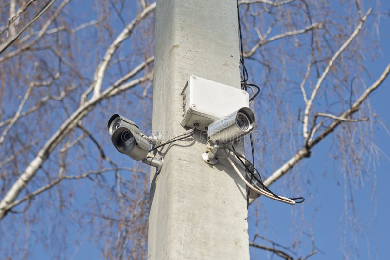 Macchine fotografiche di videosorveglianza compatte sulla posta di sostegno nelle aree pubbliche su cielo blu Videocamere di sicu fotografia stock Macchine fotografiche di videosorveglianza compatte sulla posta di sostegno nelle aree pubbliche su cielo blu Videocamere di sicu fotografia stock