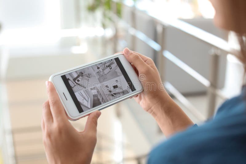 Macchine fotografiche moderne del cctv del monitoraggio della donna sullo smartphone all'interno immagini stock libere da diritti Macchine fotografiche moderne del cctv del monitoraggio della donna sullo smartphone all'interno immagini stock libere da diritti