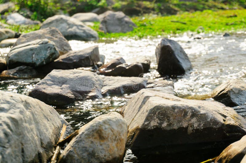 Machen Sie ringsum Felsen auf einem Riverbank mit Gras im Hintergrund glatt lizenzfreies stockbild Machen Sie ringsum Felsen auf einem Riverbank mit Gras im Hintergrund glatt lizenzfreies stockbild