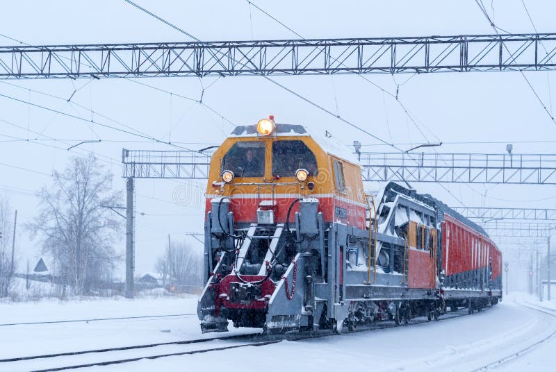 Machine ferroviaire de neige à la station pendant les chutes de neige photos stock Machine ferroviaire de neige à la station pendant les chutes de neige photos stock