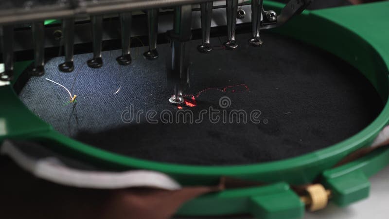 Machine à coudre de robot cnc. Une machine automatisée brode le modèle avec les fils rouges sur un tissu noir. Travaux de robotiqu banque de vidéos
