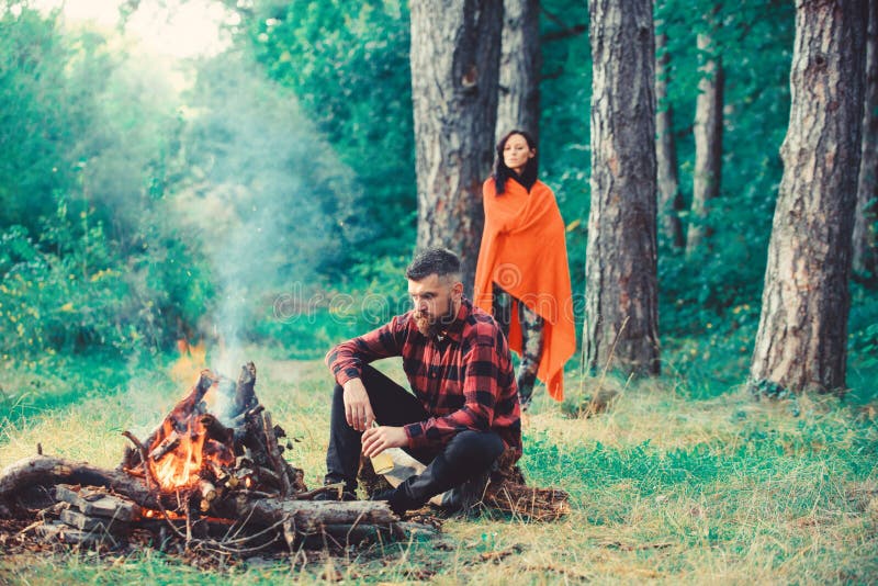 Macho avec de la bière se reposant près du feu, vacances avec l'épouse photos libres de droits Macho avec de la bière se reposant près du feu, vacances avec l'épouse photos libres de droits