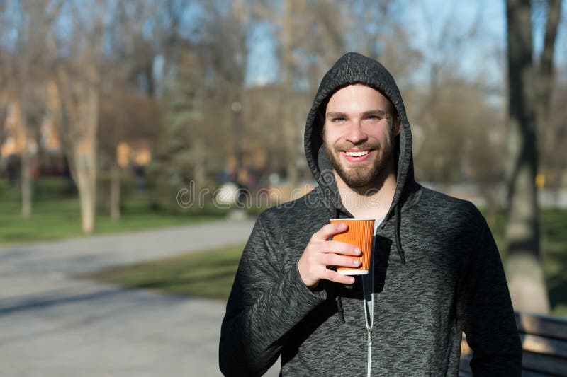 Macho felice in tazza di caffè eliminabile della tenuta del cappuccio in parco soleggiato Sorriso barbuto dell'uomo con la bevand fotografie stock libere da diritti Macho felice in tazza di caffè eliminabile della tenuta del cappuccio in parco soleggiato Sorriso barbuto dell'uomo con la bevand fotografie stock libere da diritti