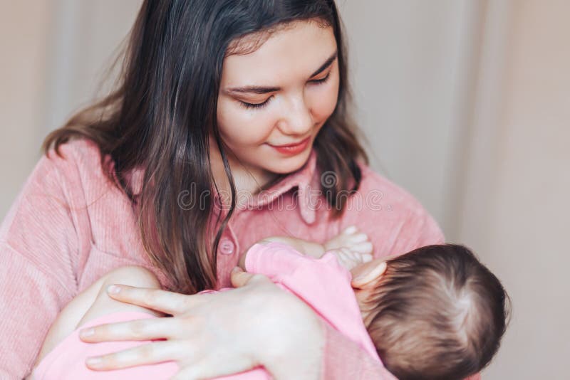 Young mother holding her little child. Mom nursing baby. Woman and new born girl relax. Mother breast feeding baby. Family at home. Young mother holding her little child. Mom nursing baby. Woman and new born girl relax. Mother breast feeding baby. Family at home