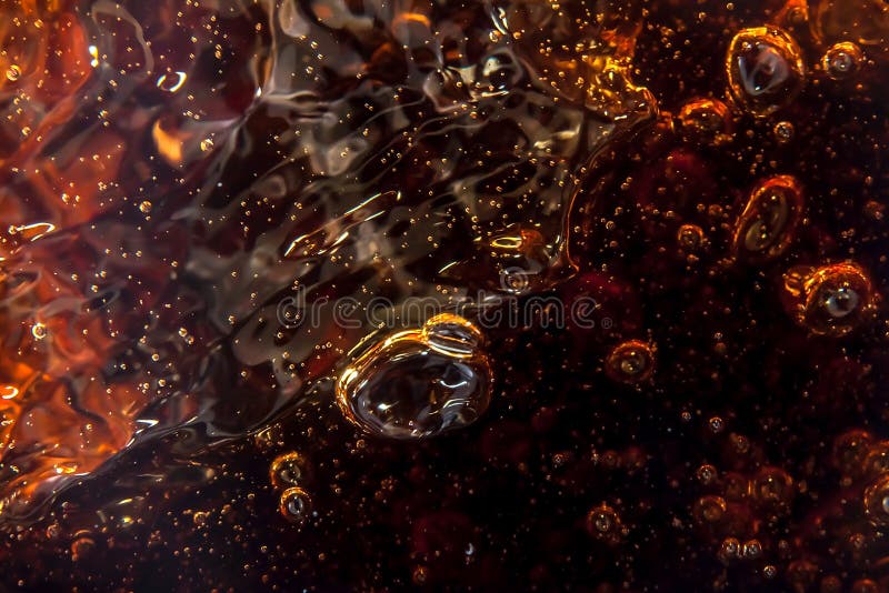 Macro black bubbles on the glass wall of cola