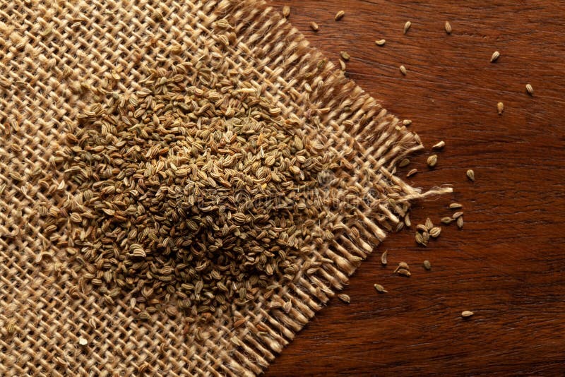 Macro close-up of Organic Ajwain seed Trachyspermum ammi or thymol seeds on the wooden top background and jute mat.