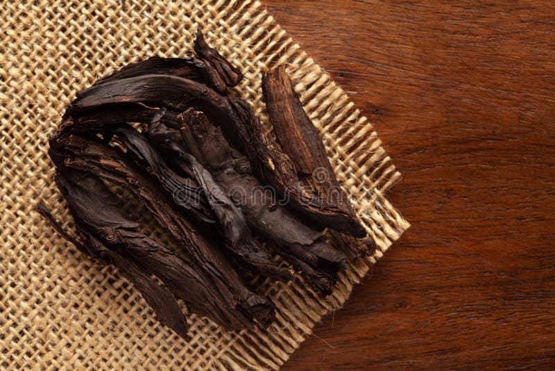 Macro close-up of Organic Alkanna tinctoria or ratan jot on the wooden top background and jute mat. Pile of Indian Aromatic Spice.