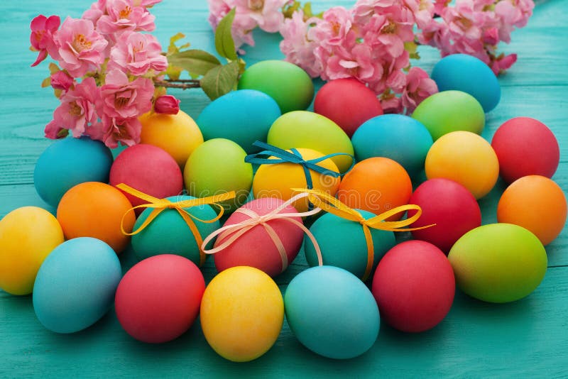 Macro Colorful Easter eggs on blue wooden kitchen table with flowers. Egg background. Selective focus royalty free stock photography