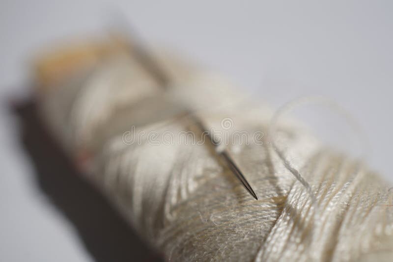 Macro Detail of a Silver Sharp Needle Inserted in the Spool of White